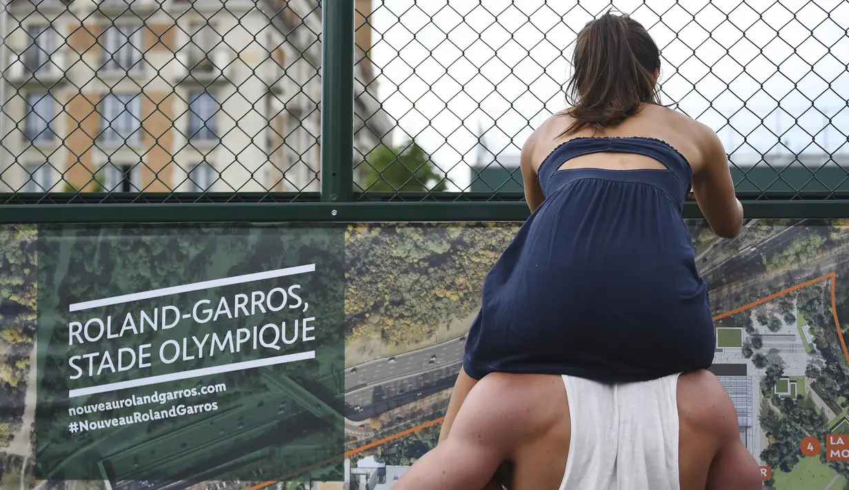 Aksi seorang wanita yang duduk di atas bahu kekasihnya saat menonton pertandingan tenis di ajang Roland Garros 2017, Prancis Terbuka, Paris,  (28/5/2017).  (AFP/Gabriel Bouys)