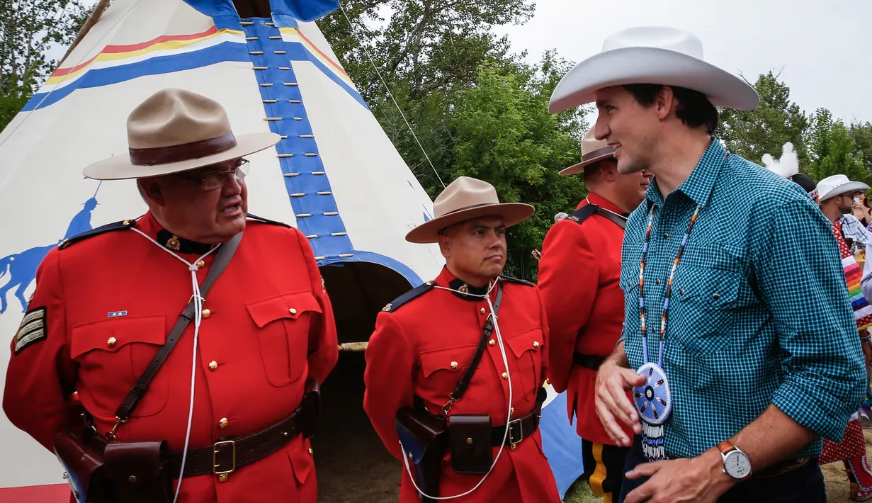 Perdana Menteri Kanada Justin Trudeau berbincang dengan Royal Canadian Mounted Police dalam acara Calgary Stampede di Calgary, Alberta, Kanada (15/7). (Jeff McIntosh / The Canadian Press via AP)