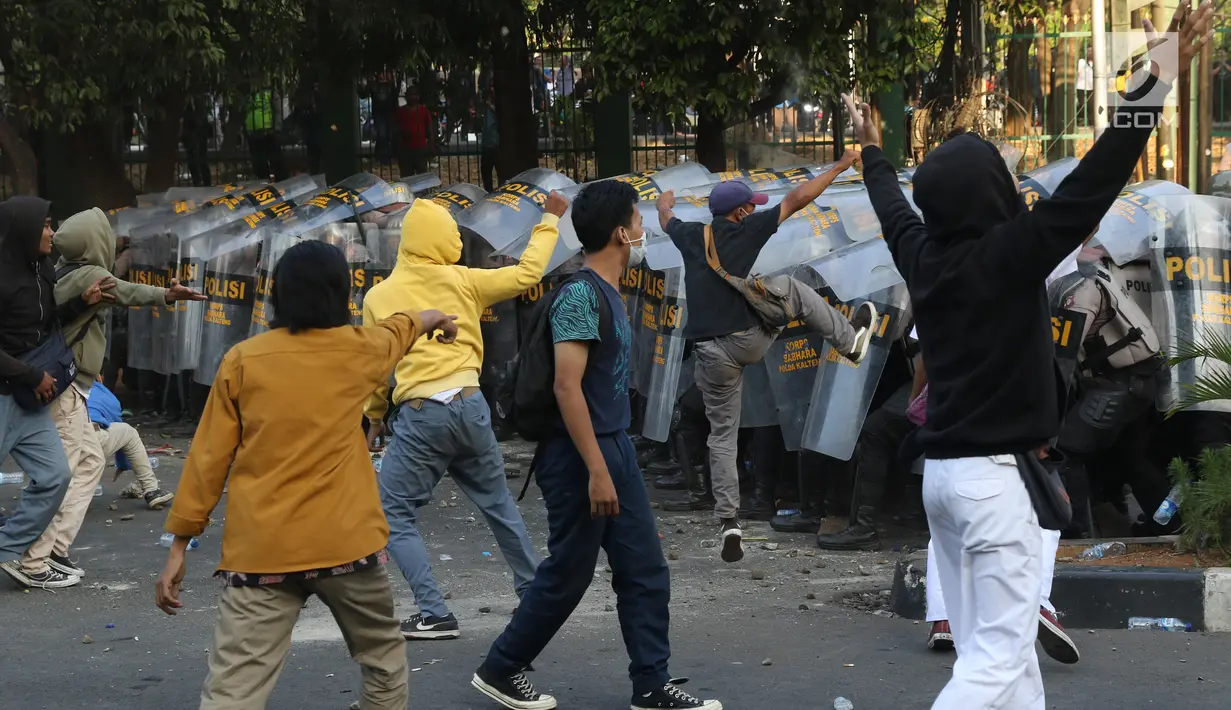 Massa melempar batu ke arah polisi yang membentuk barikade dengan tameng di sekitaran Gedung DPR RI, Jakarta, Senin (30/9/2019). Kericuhan pecah lantaran massa yang kebayakan terdiri dari pelajar tersebut berusaha masuk ke area depan DPR. (Liputan6.com/Angga Yuniar)