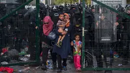 Imigran wanita dan anak-anak berhasil dievakuasi petugas dari bentrokan yang terjadi antara polisi dengan imigran yang berusaha menerobos pintu perbatasan Serbia dan Hungaria di Roszke, Rabu (16/9/2015). (REUTERS/Marko Djurica)