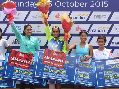 Pelari Nasional, Triyaningsih (tengah) mengangkat tangan usai menerima hadiah lomba lari Jakarta Marathon 2015 di Silang Monas Jakarta, Minggu (25/10/2015). Triyaningsih mencatat waktu tiga jam lima menit 24 detik. (Liputan6.com/Helmi Fithriansyah)