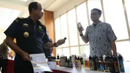 Direktur Jenderal Bea Cukai Heru Pambudi mengecek liquid vape usai memberikan izin perdana berupa Nomor Pokok Pengusaha Barang Kena Cukai (NPPBKC) kepada beberapa pengusaha pabrik liquid vape di Jakarta, Rabu (18/7). (Liputan6.com/Angga Yuniar)