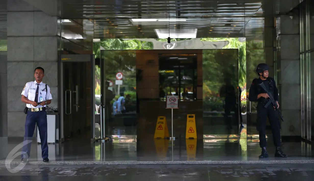 Pasca ledakan di Jalan MH Thamrin pada Kamis (14/1) lalu, aparat kepolisian bersenjata lengkap bersama seorang satpam menjaga pintu masuk Menara Cakrawala, Jakarta, Sabtu (16/1). (Liputan6.com/Faizal Fanani)