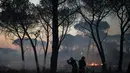 Petugas pemadam kebakaran menggunakan selang untuk memadamkan api di dekat Le Luc, Prancis selatan, Selasa (17/8/2021). Ribuan orang meninggalkan rumah, perkemahan, dan hotel di area indah yang disukai penduduk dan turis saat terjadi kebakaran. (AP Photo/Daniel Cole)