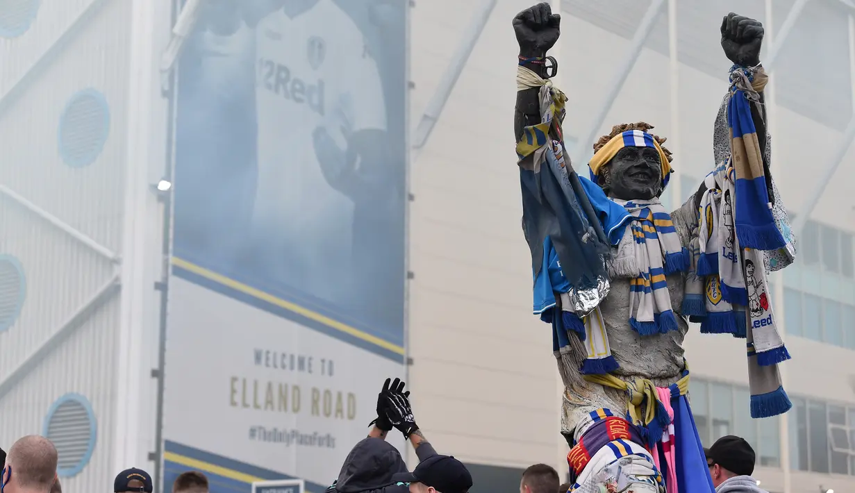 Pendukung Leeds United berkumpul di samping patung legenda klub Billy Bremner, di luar tanah Elland Road mereka untuk merayakan kembalinya klub ke Liga Premier setelah 16 tahun, di Leeds, Inggris utara (17/7/2020). (AFP/Paul Ellis)