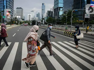 Sejumlah pekerja berjalan melintas pelican cross di kawasan Jalan Sudirman, Jakarta, Selasa (2/11/2021). Sektor non-esensial kini boleh mempekerjakan hingga 75 persen karyawannya dari kantor. Sebelumnya, angka ini dibatasi hingga 50 persen. (Liputan6.com/Faizal Fanani)