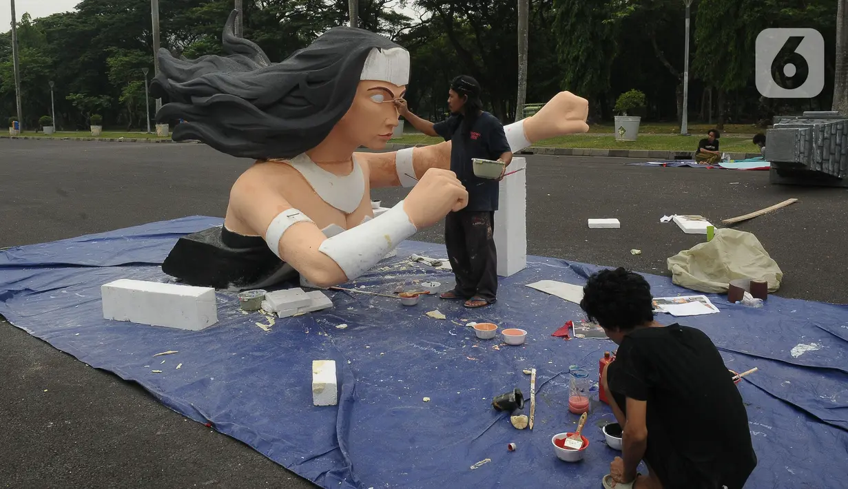 Pekerja seni menyelesaikan pembuatan patung untuk mobil hias di Silang Monas, Jakarta, Selasa (26/12/2023). (merdeka.com/Imam Buhori)