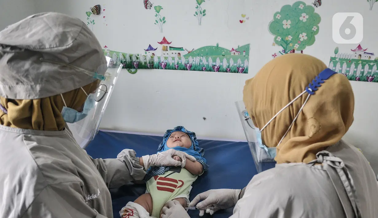 Dokter mengenakan APD lengkap saat memberikan imunisasi kepada balita di Puskesmas Kecamatan Jatinegara, Jakarta, Kamis (26/11/2020). (merdeka.com/Iqbal S. Nugroho)
