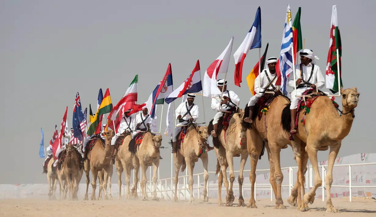 <p>Parade unta dengan bendera saat Kontes Kecantikan Unta di Qatar Camel Mzayen Club, Ash-Shahaniyah, Qatar, 2 Desember 2022. Bersamaan dengan pesta sepak bola Piala Dunia 2022, Qatar juga menggelar Kontes Kecantikan Unta. (AP Photo/Alessandra Tarantino)</p>
