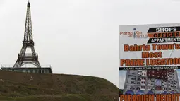 Sebuah spanduk terlihat dipasang dengan latar belakang replika Menara Eiffel yang berdiri di bukit Kota Bahria, pinggiran Islamabad, Pakistan, 16 Maret 2016. Replika tersebut memiliki tinggi mencapai 80 meter. (REUTERS/Caren Firouz)