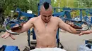 Valentyn (25) mengangkat beban saat berlatih fitnes di sebuah gym outdoor di Ibu Kota Ukraina, Kiev, 18 Agustus 2017. Alat olahraga di gym tersebut dibuat seorang teknisi bernama Yuri Kook pada dekade 1970-an. (GENYA SAVILOV/AFP)