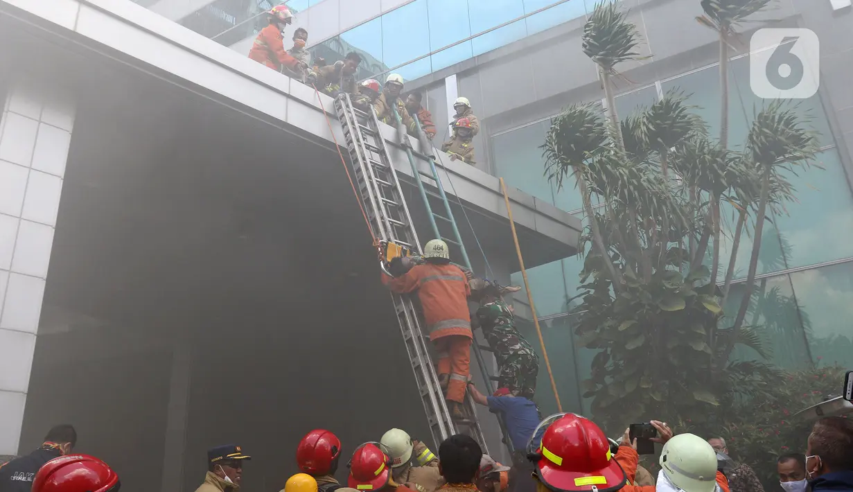 Petugas mengevakuasi korban kebakaran di Gedung Cyber 1, Jakarta, Kamis (2/12/2021). Suku Dinas Pemadam Kebakaran DKI Jakarta menurunkan 22 unit mobil pemadam kebakaran. (Liputan6.com/Herman Zakharia)