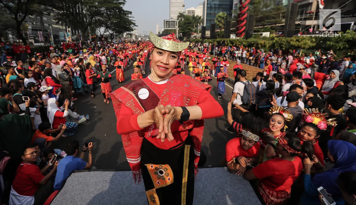 Seorang penari diikuti ribuan peserta membawakan Tari Tortor dari Sumatera Utara saat CFD di Senayan, Jakarta, Minggu (12/8). Kegiatan ini digelar menyambut HUT Ke-73 RI dan Asian Games 2018. (Liputan6.com/Fery Pradolo)