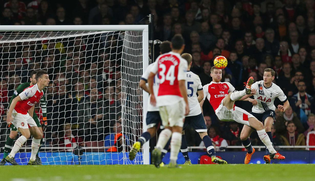 Pemain Arsenal Per Mertesacker melakukan tembbakan salto saat dihadang para pemain Tottenham Hotspur pada lanjutan Liga Premier Inggris  di Stadion Emirates, London, Inggris, Minggu (8/11/2015). Arsenal bermain imbang 1-1.   (Reuters / Eddie Keogh)