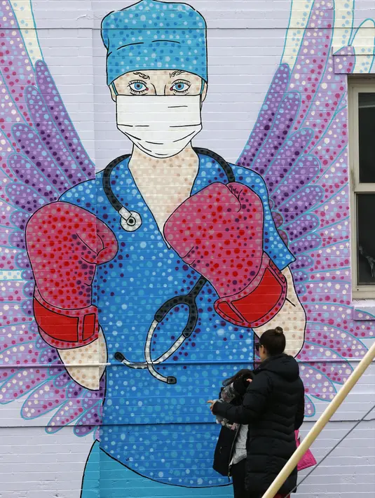 Seorang wanita dan anak-anak berjalan melewati mural yang menggambarkan seorang perawat bermasker mengenakan sarung tinju karena pandemi virus corona COVID-19 di East Colfax Avenue, Denver, Amerika Serikat, Rabu (15/4/2020). (AP Photo/David Zalubowski)