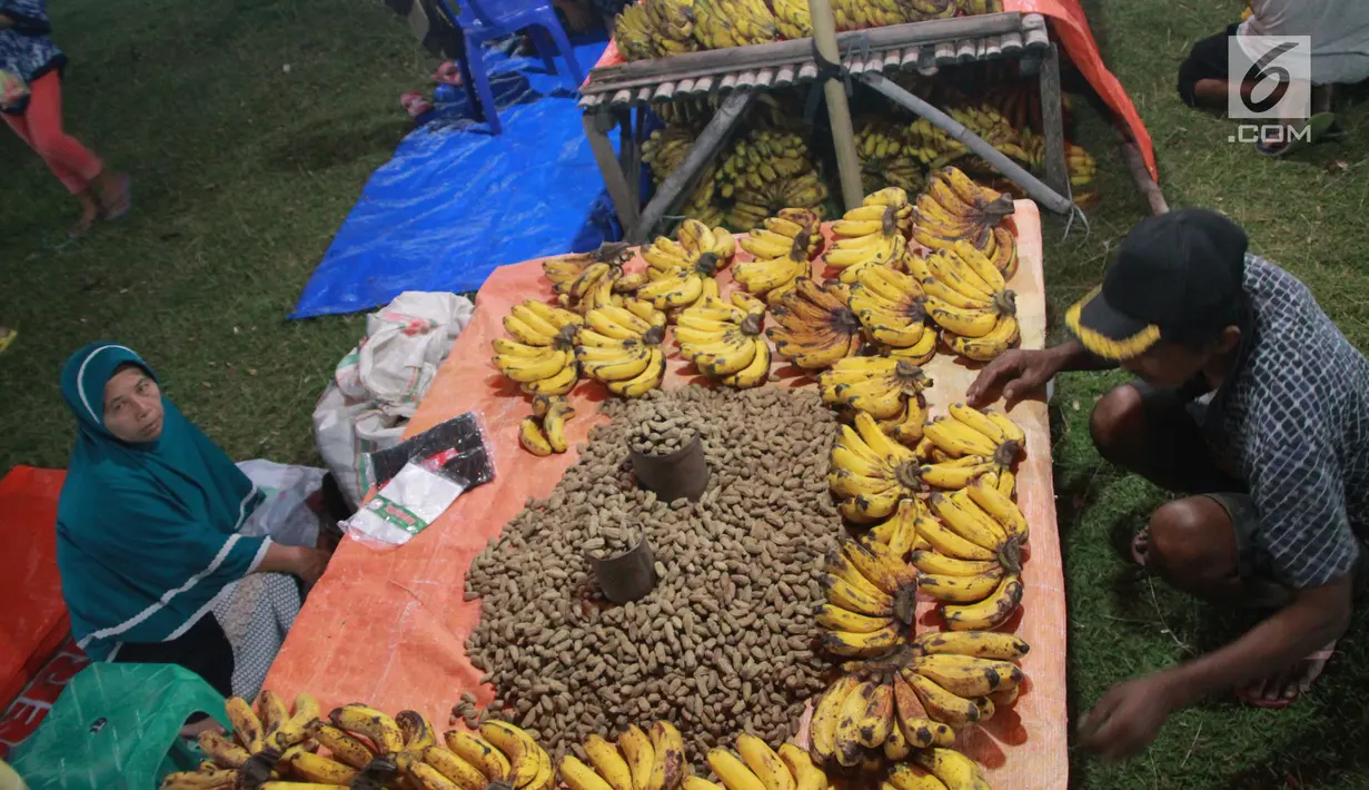 Pedagang menjual pisang dan kacang di pasar malam pada tradisi Malam Qunut di Desa Payunga, Kec. Batudaa, Kab. Gorontalo, Senin (20/5/2019). Tradisi Malam Qunut di Gorontalo dilakukan pada setiap pertengahan bulan Ramadan dengan beramai-ramai memakan pisang dan kacang. (Liputan6.com/Arfandi Ibrahim)