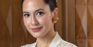 Pevita Pearce tampil memesona mengenakan atasan kebaya brokat putih lengan panjang sebagai inner dipadukan buister warna biru yang dihiasi bros besar serasi dengan anting-anting dan hiasan rambutnya. [ @pevpearce]