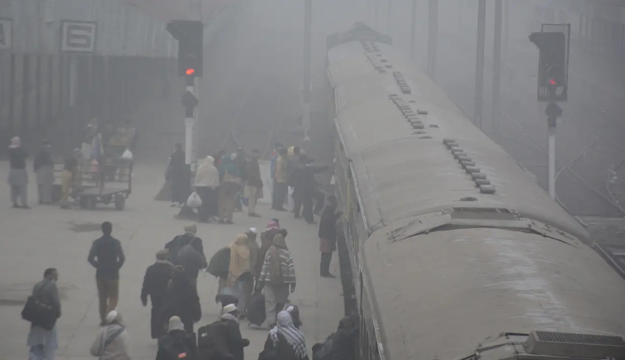 Para penumpang menaiki kereta di tengah kabut tebal di sebuah stasiun kereta api di Kota Lahore, Pakistan timur, pada 13 Desember 2020. Kabut tebal menyelimuti sejumlah kota di Pakistan, sehingga meminimalkan jarak pandang dan mengganggu lalu lintas jalan. (Xinhua/Sajjad)