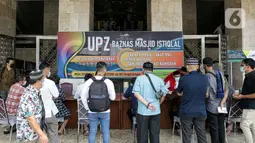 Umat muslim antre membayar zakat fitrah kepada amil zakat di Masjid Istiqlal, Jakarta, Jumat (7/5/2021). Panitia Zakat Masjid Istiqlal mulai membuka layanan pembayaran zakat fitrah dengan pembayaran senilai Rp 50 ribu atau 3,5 liter beras. (Liputan6.com/Faizal Fanani)