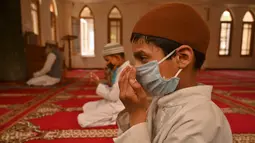 Anak-anak yatim Muslim mengenakan masker berdoa sambil menjaga jarak sosial di dalam pusat panti asuhan selama bulan suci Ramadan di Srinagar (11/5/2020). (AFP/Tauseff Mustafa)