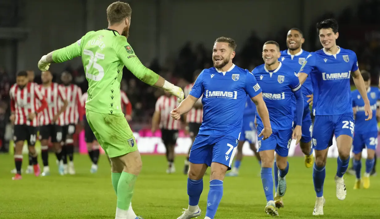 Pertandingan akhirnya dilanjutkan dengan adu penalti. Kiper Gillingham FC, Jake Turner keluar sebagai pahlawan usai berhasil menggagalkan tendangan Mikkel Damsgaard. (AP Photo/Kirsty Wigglesworth)