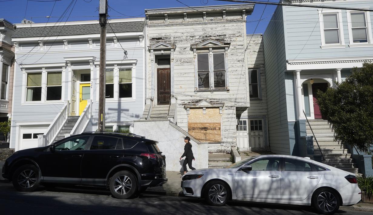 Pejalan kaki melewati rumah bergaya Victoria yang baru saja dijual di San Francisco, pada 14 Januari 2022. Rumah berusia 122 tahun yang sudah lapuk ini dipasarkan sebagai "rumah terburuk di blok terbaik" San Francisco terjual hampir 2 juta dollar AS atau sekitar Rp 28,6 miliar. (AP Photo/Jeff Chiu)