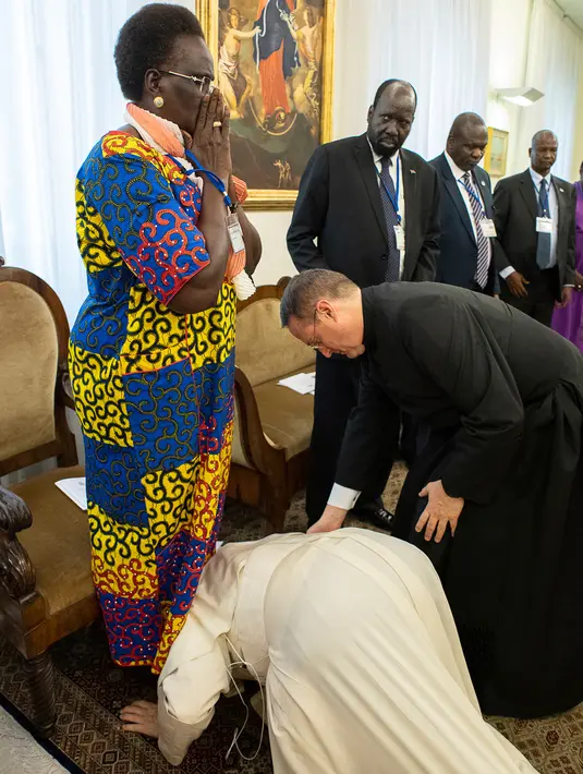 Paus Fransiskus berlutut dan mencium kaki politisi Sudan Selatan, Rebecca Nyandeng De Mabior dalam pertemuan di Vatikan, Kamis (11/4). Paus Fransiskus mencium kaki baik pejabat pemerintah maupun oposisi guna mencegah para pemimpin itu kembali ke perang saudara. (Vatican Media via AP)
