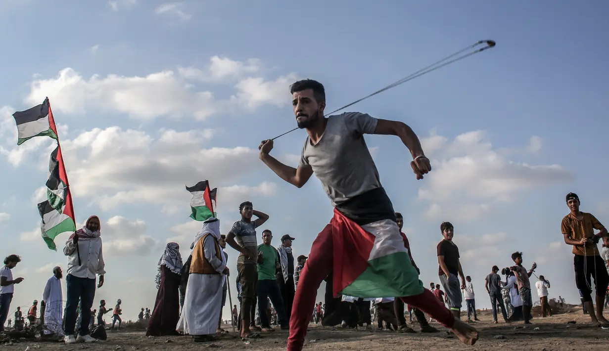 Pria Palestina memakai ketapel untuk melemparkan batu ke arah pasukan Israel saat bentrok di Khan Yunis, Jalur Gaza, Jumat (13/9/2019). Warga menyerukan pencabutan blokade Israel di Jalur Gaza. (SAID KHATIB/AFP)