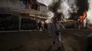 Orang-orang mencoba menyelamatkan barang-barang dari toko yang terbakar setelah serangan Rusia di Kharkiv, Ukraina, 25 Maret 2022. (AP Photo/Felipe Dana)