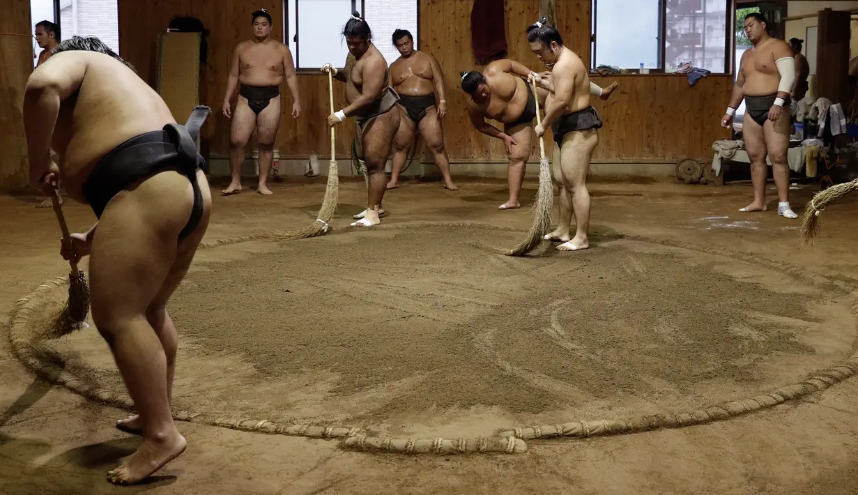 Para pegulat sumo menyapu tanah ring saat berlatih di Musashigawa Sumo Stable di Beppu, Jepang, Jumat (18/10/2019). Sumo adalah olahraga tradisional Jepang. (AP Photo/Aaron Favila)