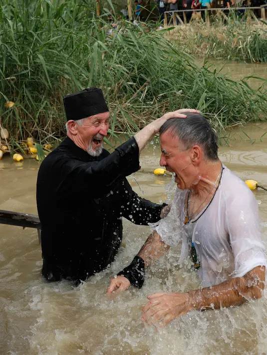 Seorang pria Kristen Ortodoks Serbia dibaptis di perairan Sungai Yordan di dekat kota Jericho (4/3). Sungai ini diyakini menjadi tempat Yesus Kristus dibaptis oleh Yohanes Pembaptis. (AFP Photo/Gali Tibbon)