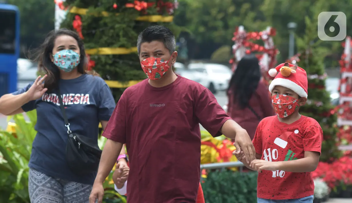 Warga DKI Jakarta melintas di dekat hiasan pohon Natal 2021 di Bundaran HI, Jakarta, Sabtu (25/12/2021). Libur Natal 2021 dimanfaatkan sebagian warga berfoto berlatar pohon Natal yang telah dihias atau berjalan-jalan ke mal untuk mengisi waktu berlibur bersama. (merdeka.com/Imam Buhori)