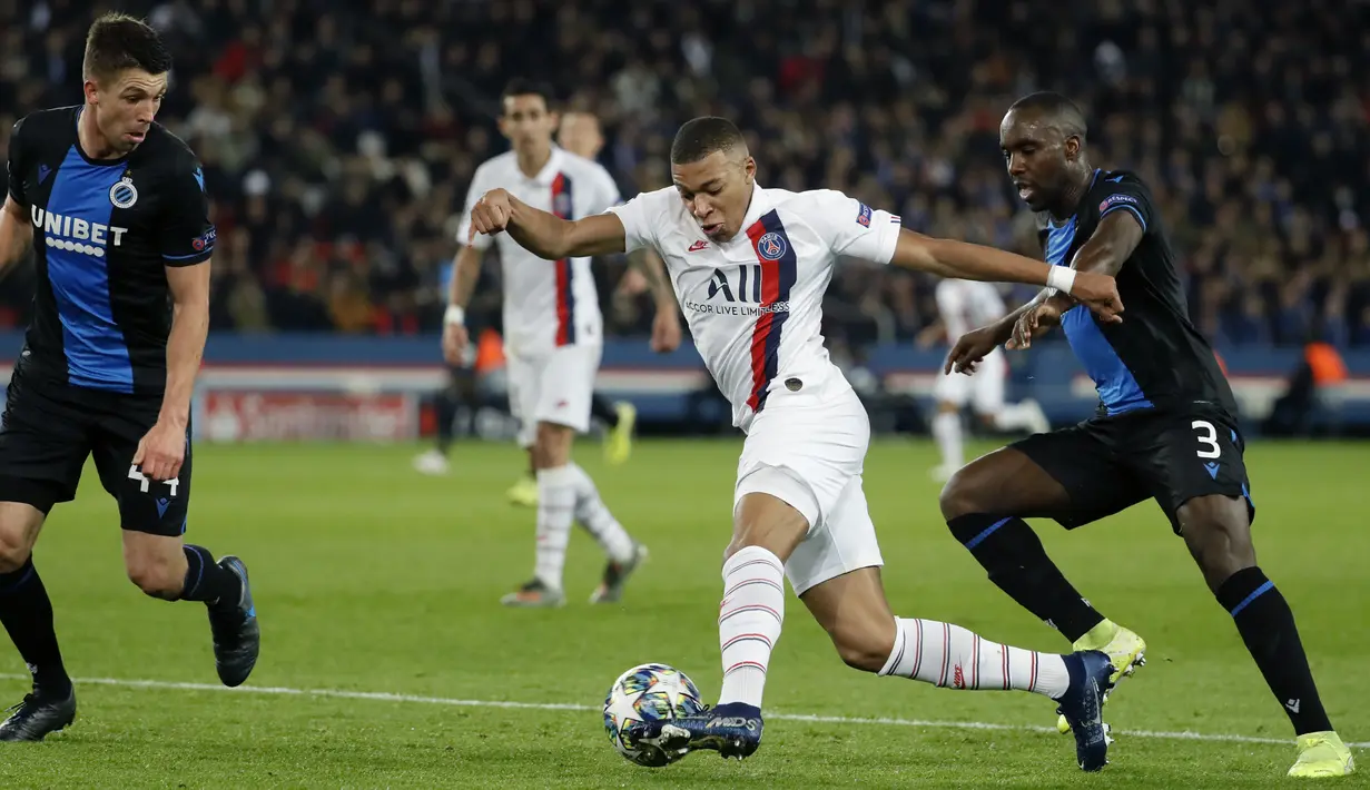 Striker Paris Saint-Germain, Kylian Mbappe menggiring bola melewati dua pemain Club Brugge pada pertandingan Grup A Liga Champions di stadion Parc des Princes di Paris (6/11/2019). PSG menang 1-0 atas Club Brugge dan melaju ke babak 16 besar. (AFP Photo/Thomas Samson)