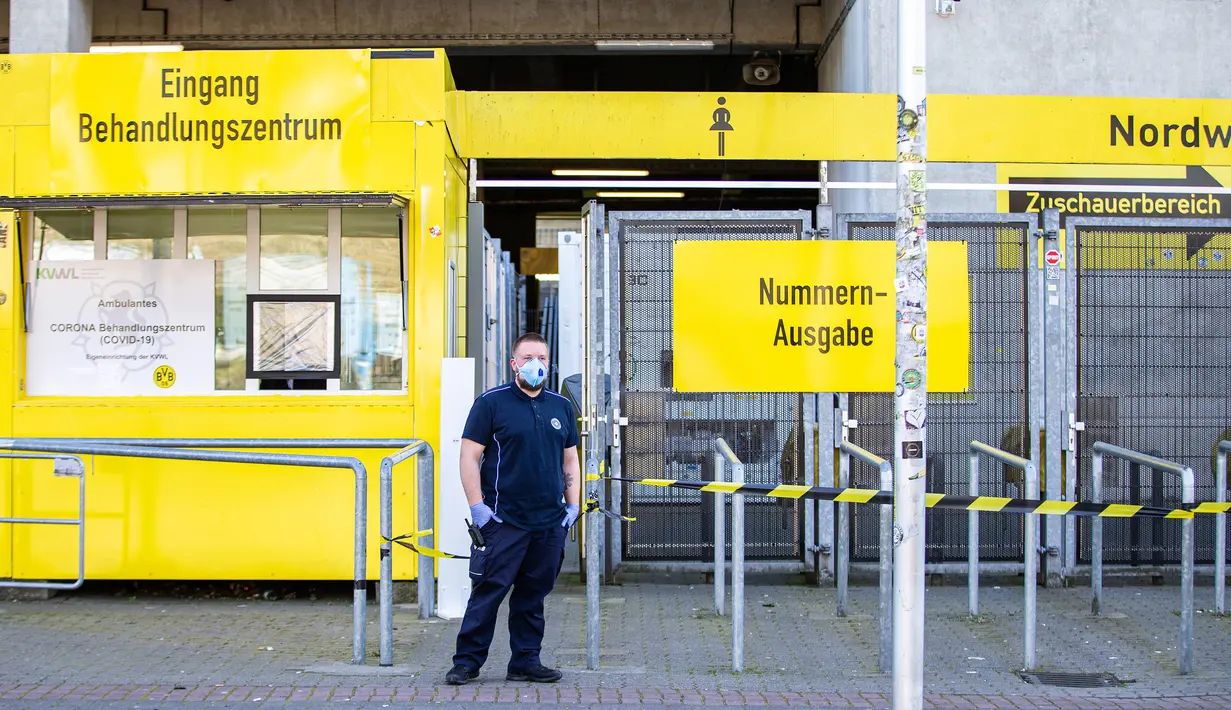 Petugas keamanan mengenakan masker berjaga-jaga di luar pusat pengujian COVID-19 di stadion milik Borussia Dortmund di Jerman (4/4/2020). Kamar-kamar di tribun utara Stadion Westfalen dipersiapkan untuk menampung orang-orang yang diduga terinfeksi COVID-19. (Xinhua/Joachim Bywaletz)