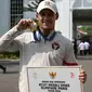 Peraih medali emas cabang olahraga angkat besi kelas -73kg putra Olimpiade Paris 2024, Rizki Juniansyah berfoto dengan medali yang diraihnya di Istana Merdeka, Jakarta, pada Kamis 15 Agustus 2024. (BAY ISMOYO/AFP)