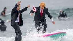 Gary Crane berselancar mengenakan kostum menyerupai Presiden AS, Donald Trump di Newport Beach, California, 28 Oktober 2017. Acara ini untuk merayakan Halloween yang jatuh pada tanggal 31 Oktober. (Paul Rodriguez/The Orange County Register via AP)