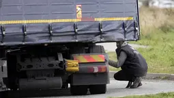 Migran berusaha bersembunyi di truk untuk menyeberangi terowongan menuju Inggris di Calais, Prancis, 14 Oktober 2021. Dalam praktik berbahaya dan berpotensi mematikan, ia mencoba melewati terowongan yang dijaga ketat yang menghubungkan kedua negara dengan bersembunyi di truk. (AP/Christophe Ena)