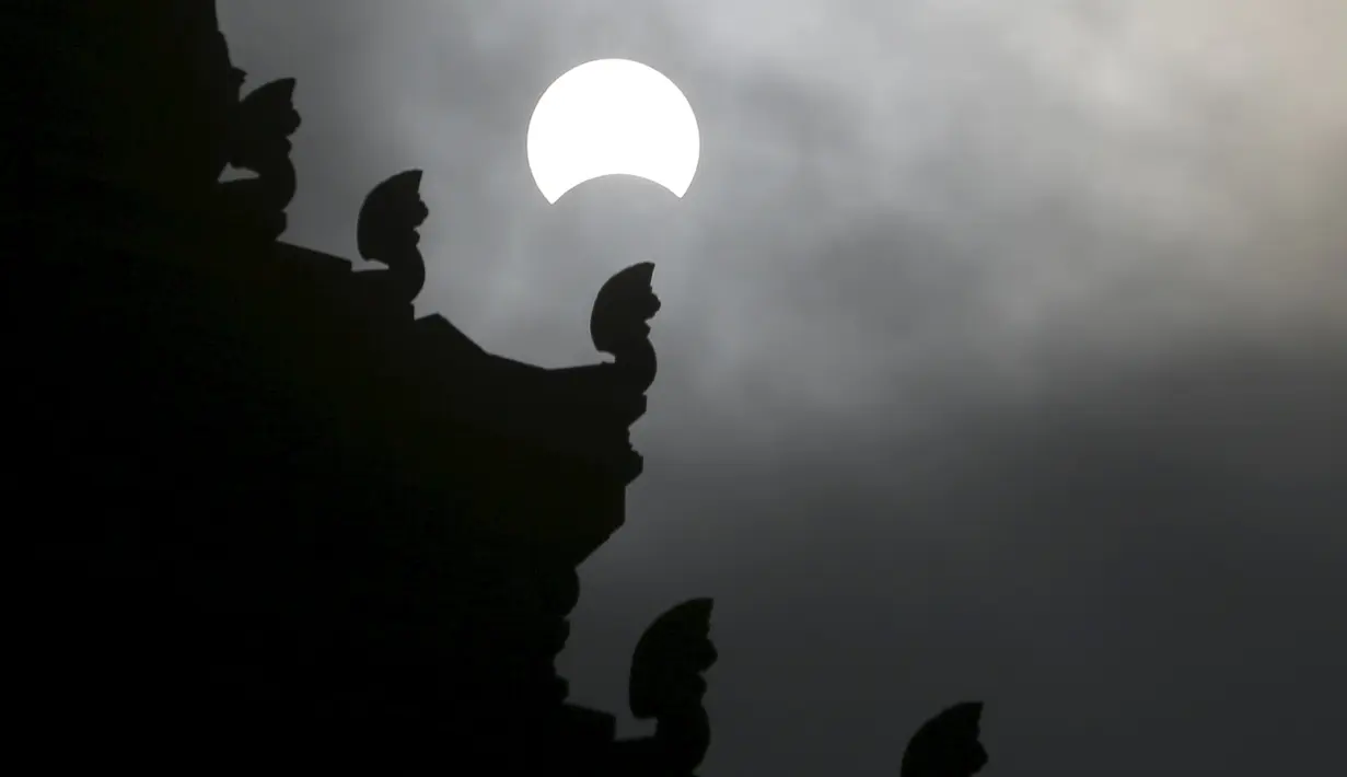 Gerhana matahari parsial terlihat di dekat Monumen Kemerdekaan di Phnom Penh, Kamboja, (9/3/2016). Gerhana matahari total terjadi di sejumlah daerah di Indonesia. (Reuters/ Samrang Pring)