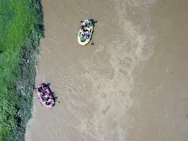 Peserta dengan perahu karet  menyusuri Sungai Ciliwung sambil membersihkan sampah pada acara Bersih-Bersih Sungai Ciliwung, Jakarta, Minggu (08/4). Kegiatan tersebut merupakan rangkaian HUT Kementerian BUMN. (Liputan6.com/Fery Pradolo)