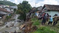 Warga bersama anggota TNI berjibaku mengangkat rangka besi jembatan yang roboh pasca diterjang banjir bandang di Kampung Cimuncang, Ciwidey, Kabupaten Bandung, Rabu (8/6/2022). (Liputan6.com/Dikdik Ripaldi)