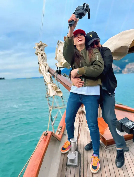 Berpelukan mesra di perahu, nampak Maia dan Irwan yang kompak kenakan padu padan jaket dan celana panjang. Sementara untuk alas kaki dipilih sneakers yang nyaman.