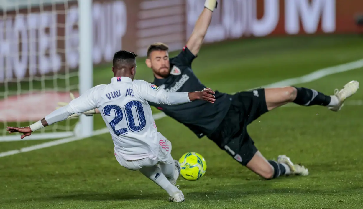 Penyerang Real Madrid, Vinicius Junior mencoba melakukan tembakan di samping kiper Athletic Bilbao Unai Simon pada pertandingan La Liga Spanyol di di stadion Alfredo Di Stefano di Madrid, Spanyol, Rabu (16/12/2020). (AP Photo/Bernat Armangue)
