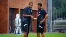 Pelatih kepala Timnas Indonesia, Patrick Kluivert (kiri) berdiskusi dengan asisten pelatih Denny Landzaat saat melakukan latihan persiapan menjelang laga Ronde 3 Kualifikasi Piala Dunia 2026 melawan China di Bali United Training Center, Bali, pada Selasa sore (23/05/2025). (Bola.com/Alit Binawan)
