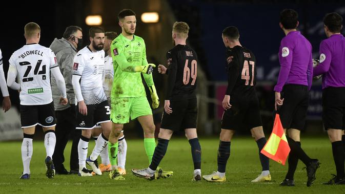 Kiper Swansea City, Freddie Woodman dan gelandang Manchester City Tommy Doyle melakukan pukulan tinju usai pertandingan perdelapan final Piala FA di di Liberty Stadium di Swansea, Wales, Kamis (11/2/2021). Kemenangan ini membuat City lolos ke perempat final Piala FA. (AFP/Pool/Rebbeca Naden)