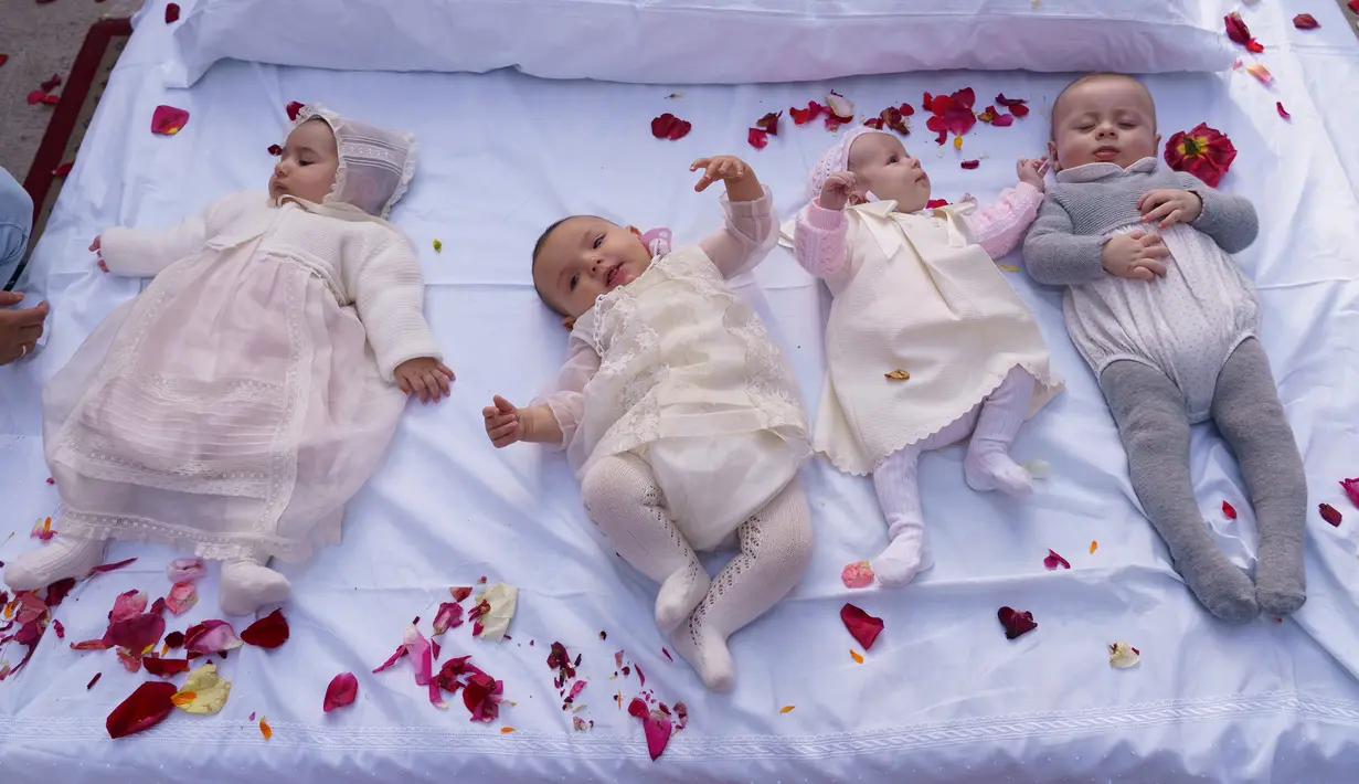 Bayi-bayi berusia hingga satu tahun ditaburi kelopak mawar sambil terlentang di atas matras usai dilompati pria berkostum setan selama tradisi melompati bayi (El Colacho) di desa Castrillo de Murcia, Spanyol, Minggu (3/6). (AFP/CESAR MANSO)