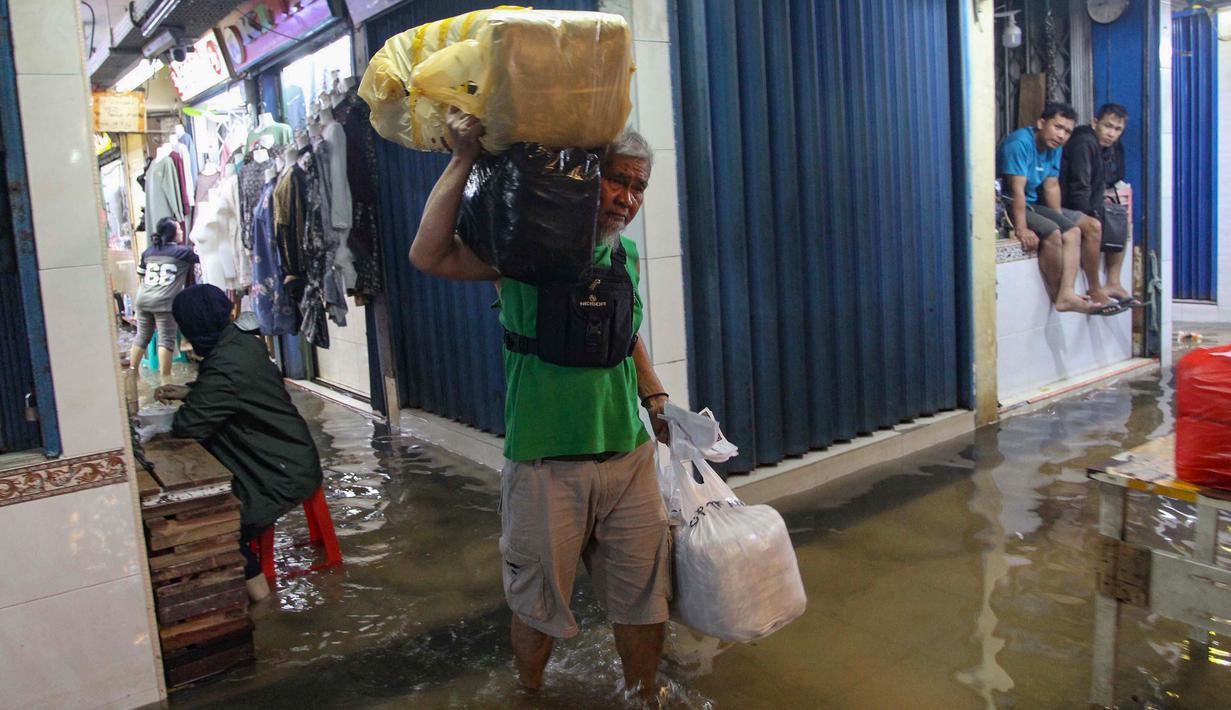 Air yang menggenang membuat mobilitas pengunjung dan distribusi barang menjadi terhambat. Tampak dalam foto, aktivitas pedagang dan pembeli di Pasar Cipulir, Jakarta, Jumat (23/1/2026). (merdeka.com/Arie Basuki)