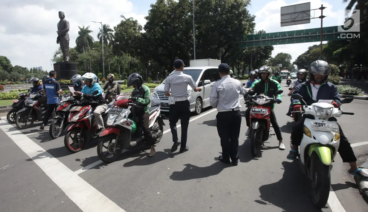 Petugas Dishub DKI Jakarta melakukan sosialisasi lajur khusus sepeda motor di Jalan MH Thamrin, Jakarta, Senin (29/1). Sosialisasi tersebut bertujuan untuk memberikan edukasi kepada warga, terutama pengendara sepeda motor. (Liputan6.com/Arya Manggala)