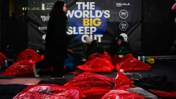 Orang-orang bersiap-siap untuk tidur di area terbuka dalam acara World's Big Sleep Out di Times Square, New York, 7 Desember 2019. Aksi yang dilakukan di beberapa kota besar dunia ini sebagai bagian dari upaya penggalangan dana untuk membantu para tunawisma di banyak negara. (Photo by AFP)