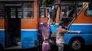 Seorang wanita melintas diantara Metromini di Terminal Blok M, Jakarta, Rabu (26/7). Menurut pihak Dishub DKI, revitalisasi tersebut melibatkan langsung para pemilik kendaraan Metromini. (Liputan6.com/Faizal Fanani)