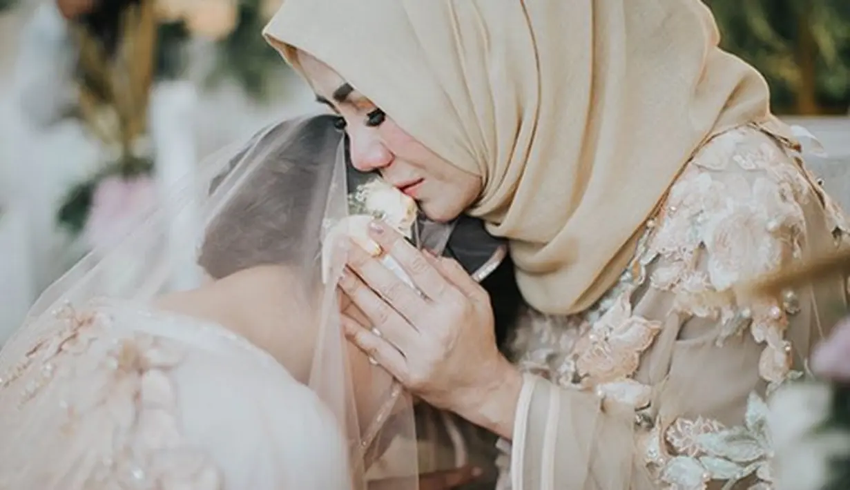 Dalam foto kedua, terlihat Syahnaz bersimpuh di depan ibundanya, Ami Qanita. Raut kesedihan dalam foto Ami yang tidak lama lagi akan melepas putrinya untuk membina rumah tangga bersama kekasihnya. (Instagram/syahnazs)
